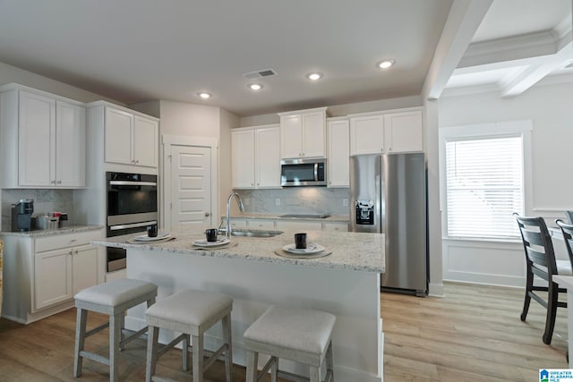 kitchen with light hardwood / wood-style floors, white cabinetry, backsplash, and appliances with stainless steel finishes