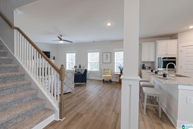 kitchen featuring ceiling fan, crown molding, white cabinetry, light hardwood / wood-style flooring, and oven