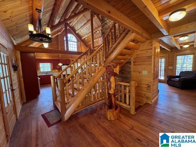 stairs featuring hardwood / wood-style flooring, vaulted ceiling with beams, wood ceiling, and wooden walls