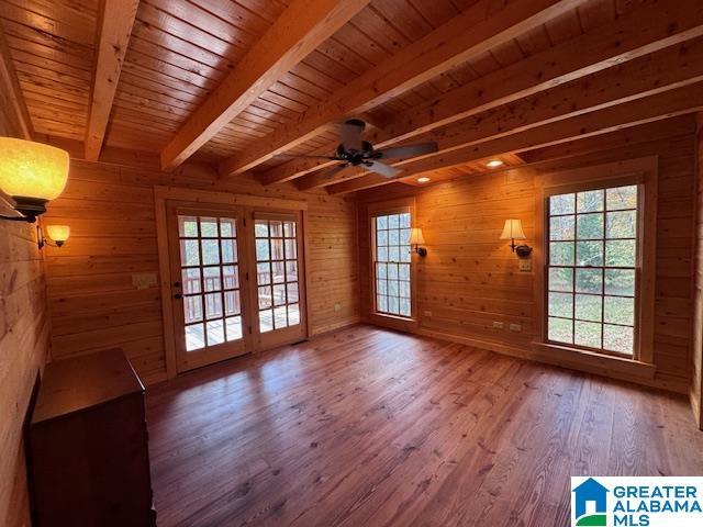 interior space featuring ceiling fan, beam ceiling, hardwood / wood-style flooring, wooden ceiling, and wood walls