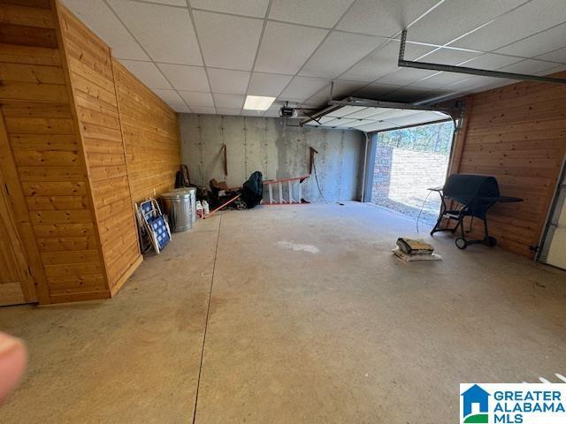 basement with wooden walls and a drop ceiling