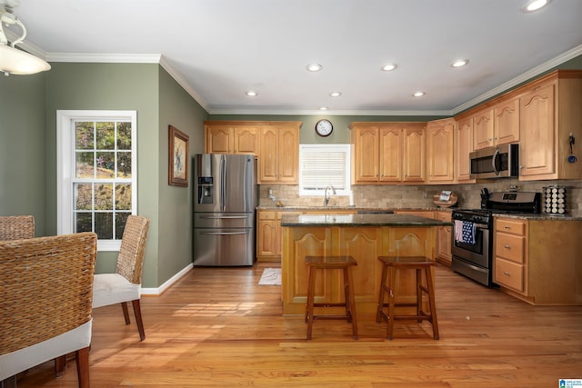 kitchen featuring sink, a kitchen island, appliances with stainless steel finishes, tasteful backsplash, and light hardwood / wood-style floors