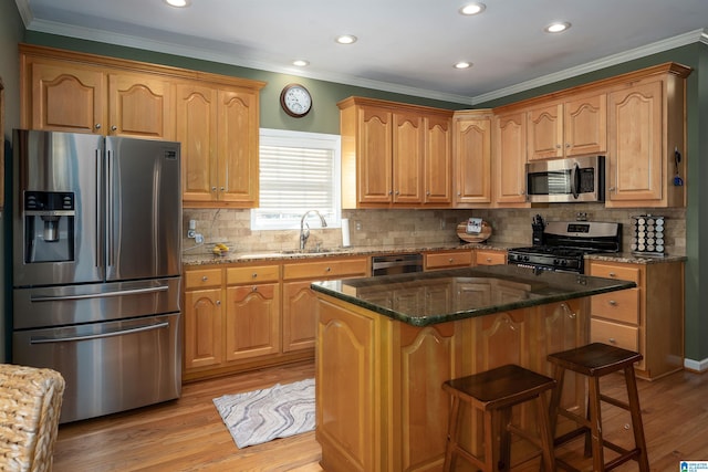 kitchen with sink, a kitchen island, light wood-type flooring, and appliances with stainless steel finishes