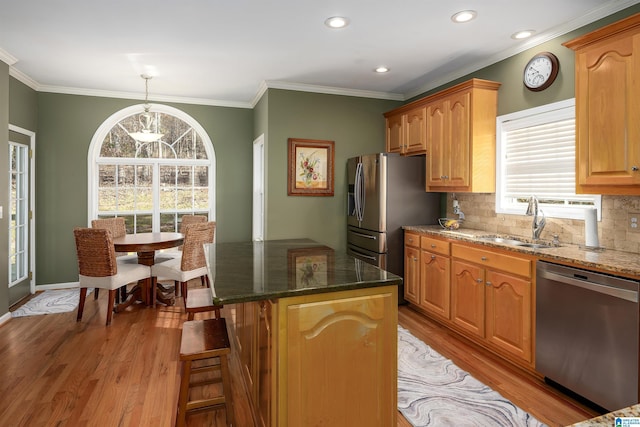 kitchen featuring a center island, sink, light wood-type flooring, decorative light fixtures, and stainless steel appliances