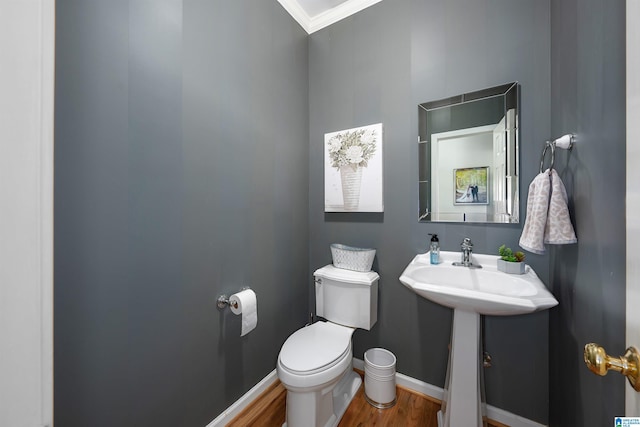 bathroom with wood-type flooring, toilet, crown molding, and sink