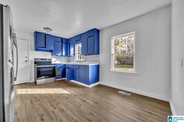 kitchen with blue cabinetry, stainless steel appliances, light hardwood / wood-style flooring, and tasteful backsplash