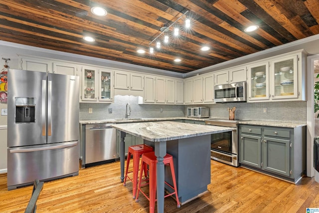 kitchen featuring a center island, light hardwood / wood-style flooring, decorative backsplash, light stone counters, and stainless steel appliances