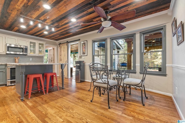 dining space with a barn door, ceiling fan, wood ceiling, and light wood-type flooring