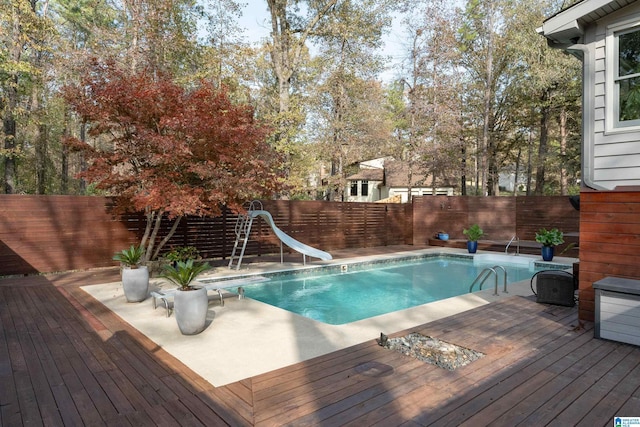 view of pool with a water slide and a deck