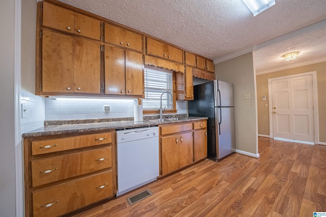 kitchen featuring stainless steel fridge, light wood-type flooring, ornamental molding, white dishwasher, and sink