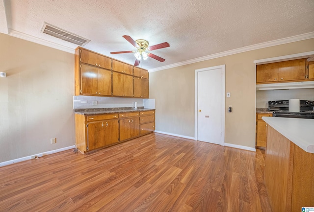 kitchen with crown molding, light hardwood / wood-style flooring, ceiling fan, a textured ceiling, and gas stove