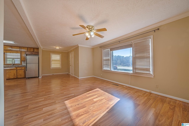 unfurnished living room featuring ceiling fan, crown molding, a textured ceiling, and light hardwood / wood-style flooring