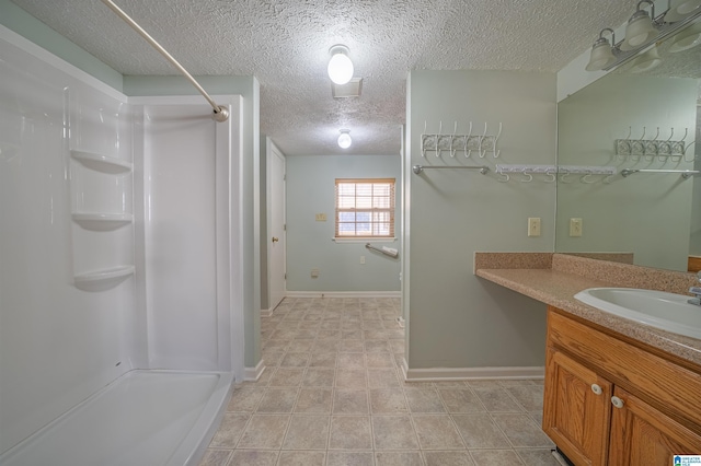 bathroom with a shower, vanity, and a textured ceiling