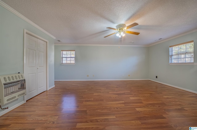 empty room featuring a textured ceiling, heating unit, hardwood / wood-style flooring, and ornamental molding