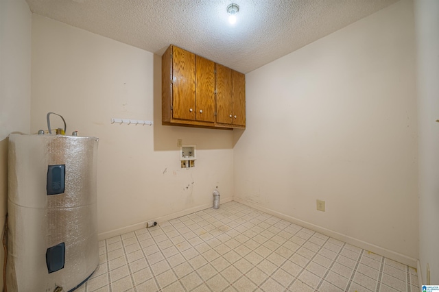 clothes washing area with electric water heater, cabinets, and a textured ceiling