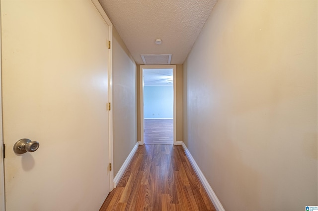 hallway with hardwood / wood-style floors and a textured ceiling