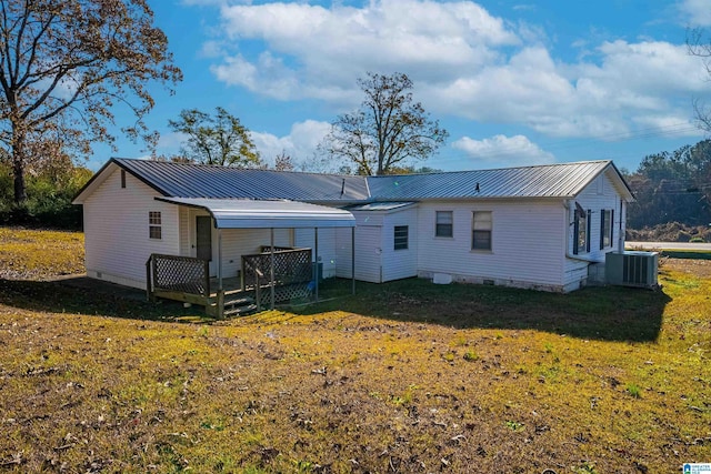 back of property with central AC unit, a wooden deck, and a lawn