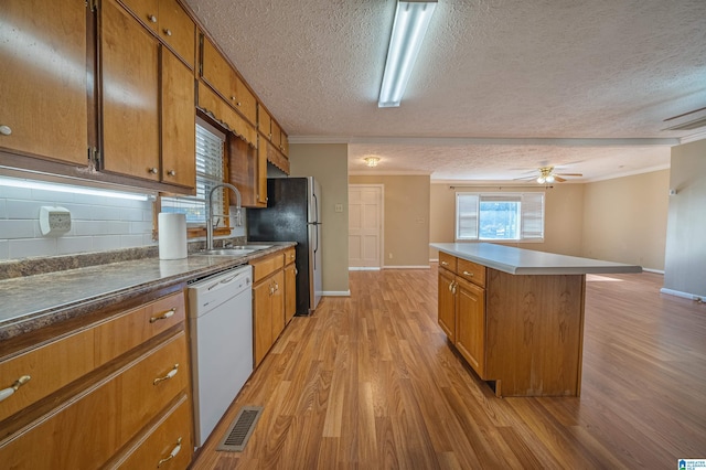 kitchen featuring crown molding, sink, white dishwasher, and light hardwood / wood-style floors