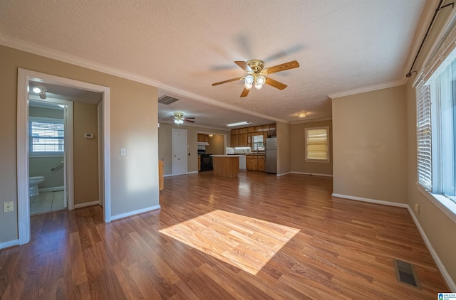 unfurnished living room with wood-type flooring, a textured ceiling, ceiling fan, and ornamental molding