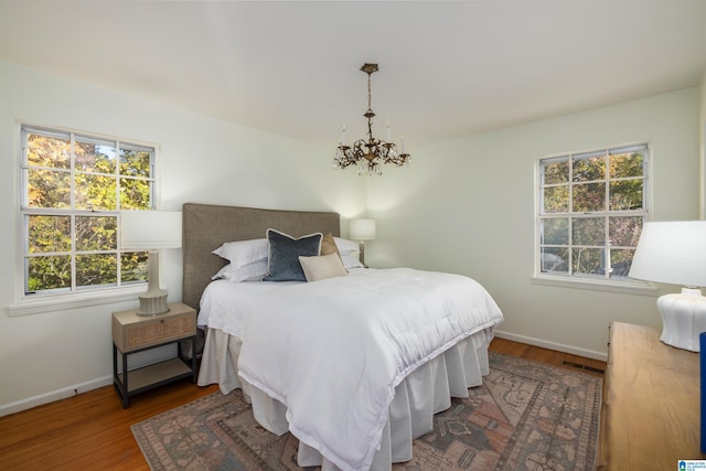 bedroom featuring a notable chandelier and dark wood-type flooring