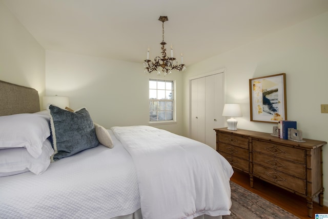 bedroom featuring a closet, dark wood-type flooring, and an inviting chandelier