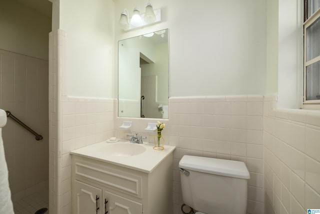 bathroom featuring tiled shower, vanity, toilet, and tile walls