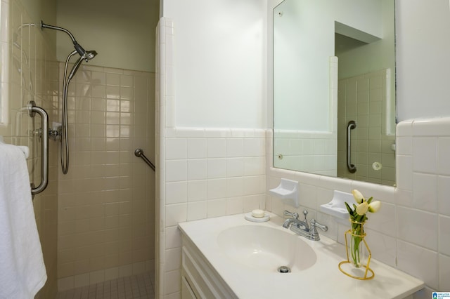 bathroom with vanity, a tile shower, and tile walls