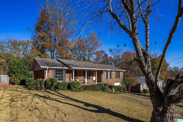 ranch-style house featuring a front lawn, covered porch, and a garage