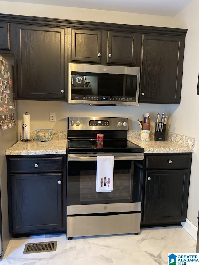 kitchen featuring light stone countertops, dark brown cabinetry, and stainless steel appliances