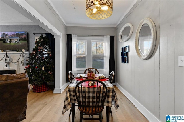 dining room featuring crown molding, light hardwood / wood-style flooring, and wood walls