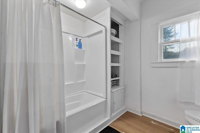 bathroom featuring toilet, shower / bathtub combination with curtain, and hardwood / wood-style flooring