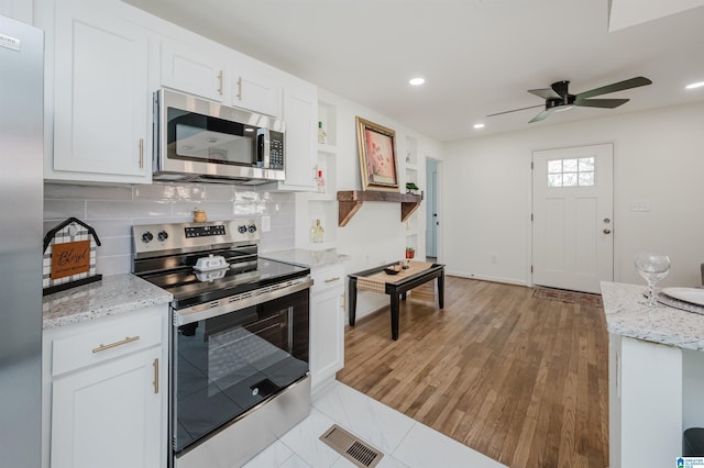 kitchen featuring white cabinets, appliances with stainless steel finishes, light hardwood / wood-style floors, and ceiling fan