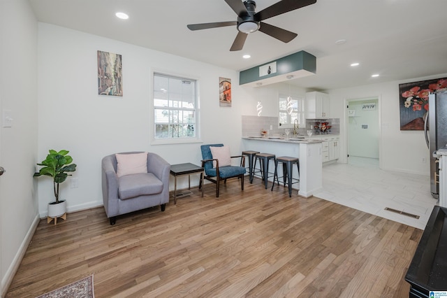 living area featuring ceiling fan, light wood-type flooring, and sink