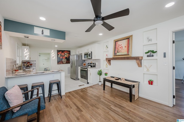 7321 Naples Ave, Birmingham, AL 35206 - kitchen featuring appliances with stainless steel finishes, white cabinetry, a peninsula, backsplash, and light wood-style floors