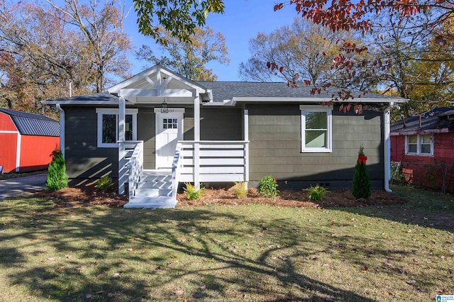 view of front of home featuring a front lawn and a storage shed