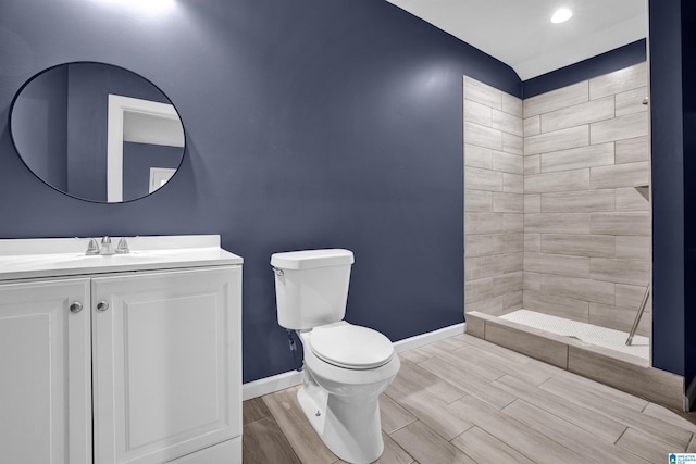 bathroom with tiled shower, vanity, hardwood / wood-style flooring, and toilet