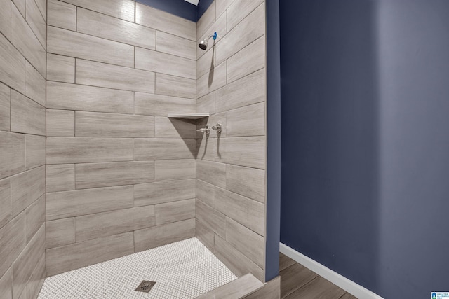 bathroom with hardwood / wood-style floors and a tile shower