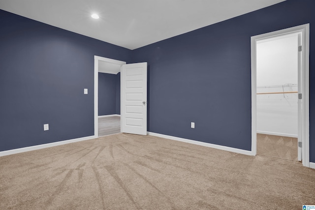 unfurnished bedroom featuring a walk in closet, light carpet, and a closet