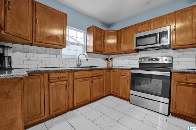 kitchen featuring appliances with stainless steel finishes, tasteful backsplash, dark stone counters, and sink