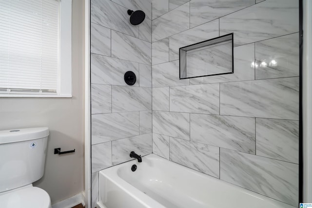 bathroom with tiled shower / bath combo and toilet