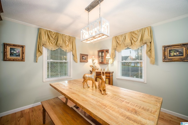 dining space with a textured ceiling, light hardwood / wood-style floors, and ornamental molding