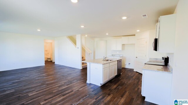 kitchen with appliances with stainless steel finishes, dark hardwood / wood-style flooring, sink, white cabinets, and an island with sink