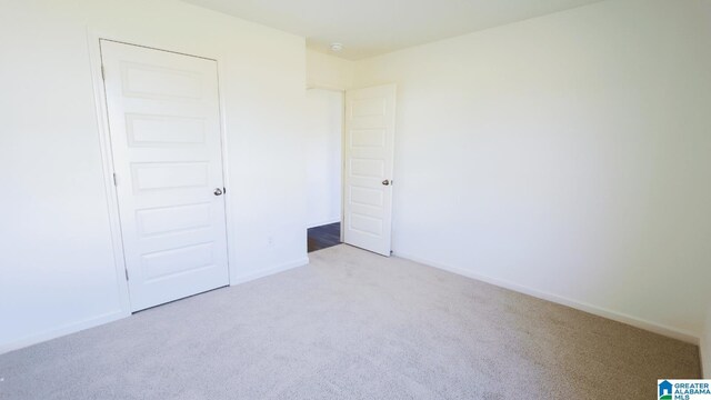 unfurnished bedroom featuring light carpet and a closet