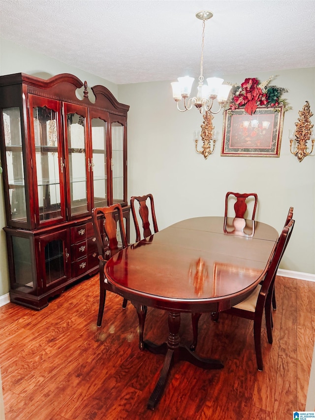 dining room featuring hardwood / wood-style flooring, a textured ceiling, and a chandelier