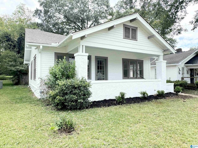 view of side of home with a yard and a porch