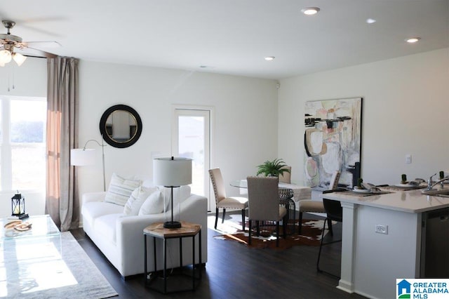 living room featuring plenty of natural light, ceiling fan, sink, and dark wood-type flooring