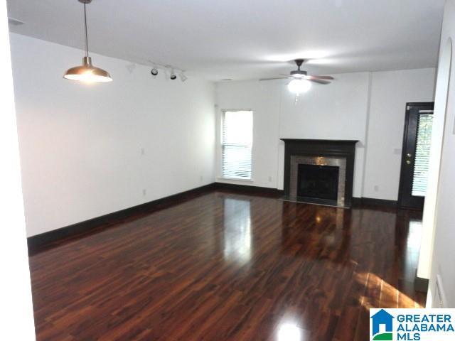 unfurnished living room with ceiling fan and dark wood-type flooring