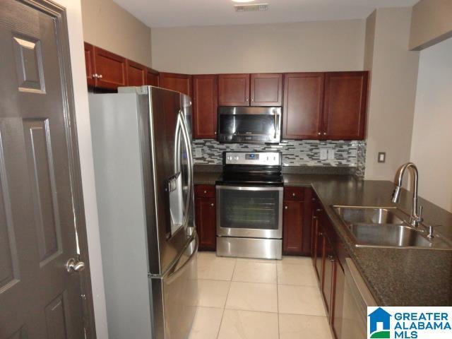 kitchen featuring backsplash, light tile patterned floors, sink, and appliances with stainless steel finishes