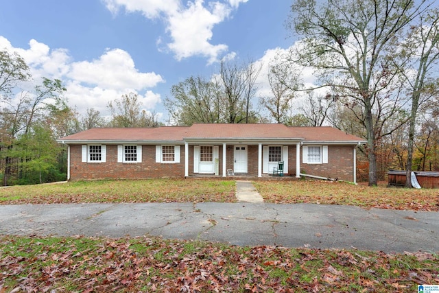 ranch-style home featuring covered porch and a front lawn