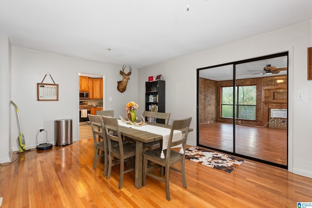 dining room with ceiling fan, cooling unit, brick wall, and light wood-type flooring